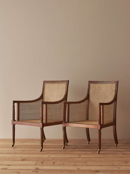 Pair of antique bergère chairs raised on brass castors