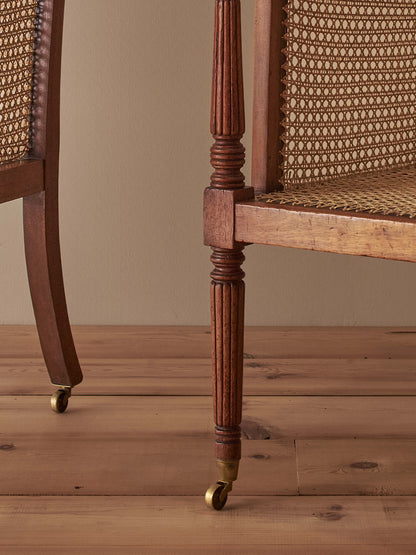 Pair of antique bergère chairs raised on brass castors