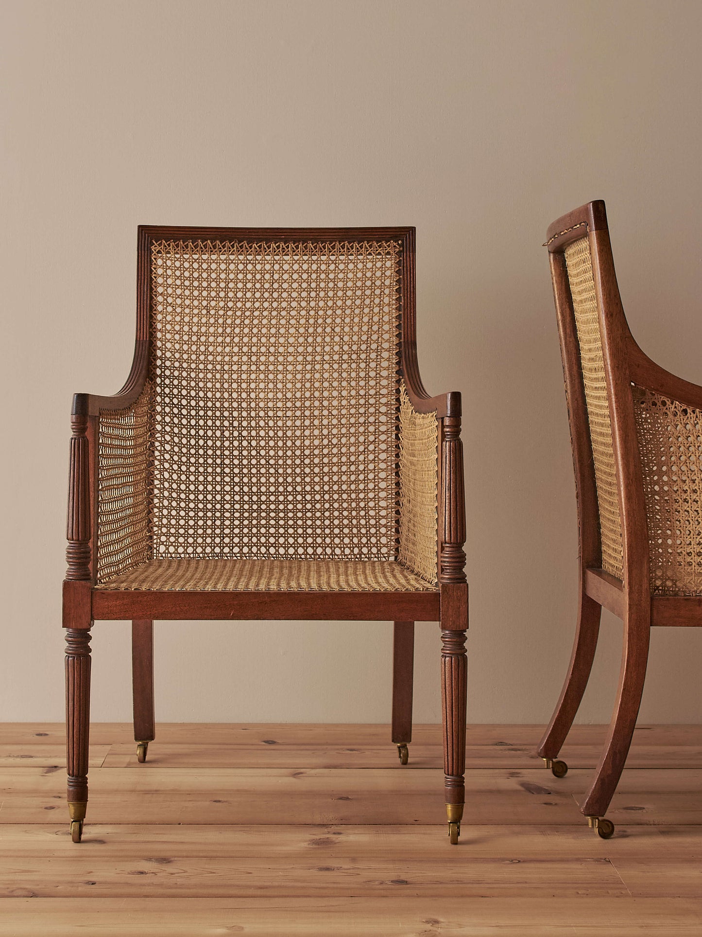 Pair of antique bergère chairs raised on brass castors