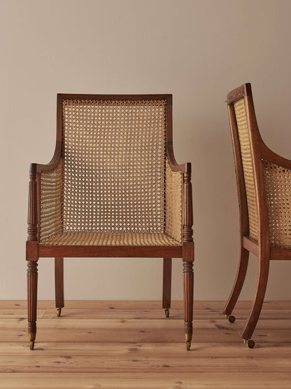 Pair of antique bergère chairs raised on brass castors